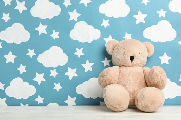 Teddy bear on white wooden table near wall with painted blue sky — Stock Photo, Image