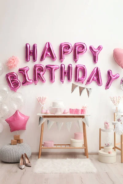 Phrase HAPPY BIRTHDAY made of pink balloon letters in decorated room