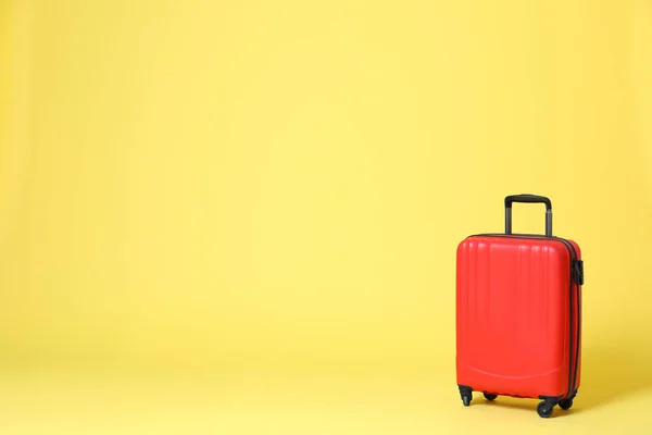 Stylowa czerwona walizka na żółtym tle. Miejsce na tekst — Zdjęcie stockowe