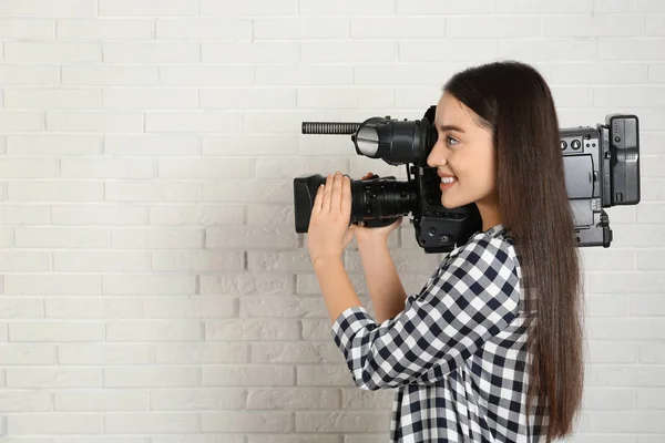 Operador con videocámara profesional cerca de pared de ladrillo blanco —  Fotos de Stock