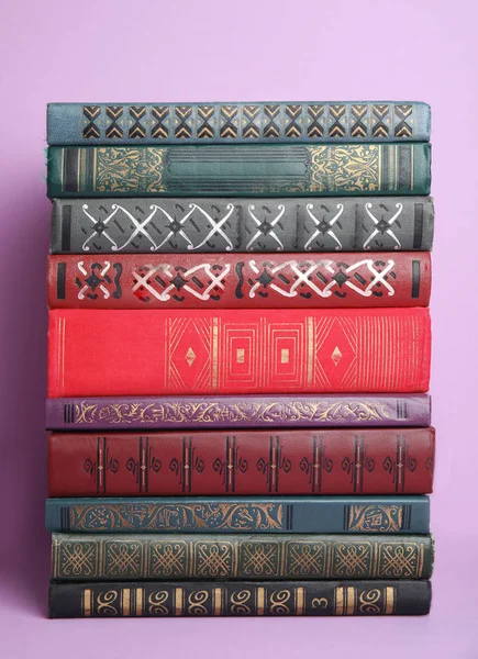 Stack of different hardcover books on violet background