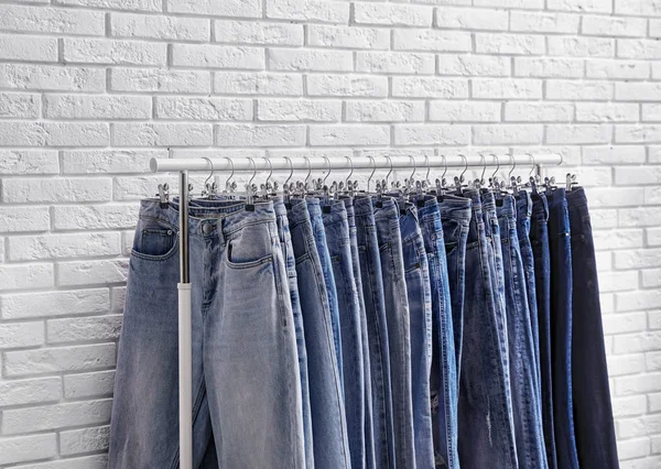 Cremalheira com jeans elegantes perto da parede de tijolo, close-up — Fotografia de Stock