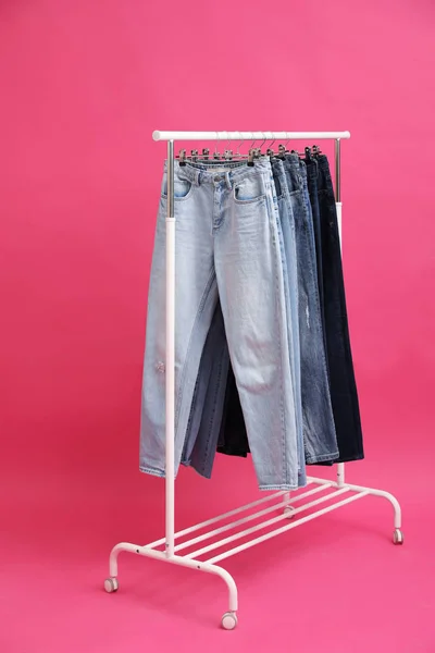 Cremalheira com jeans elegantes no fundo rosa — Fotografia de Stock