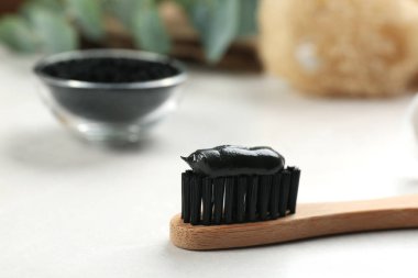Bambu diş fırçası ve beyaz masa üzerinde kömür macunu, yakın plan. Metin için boşluk