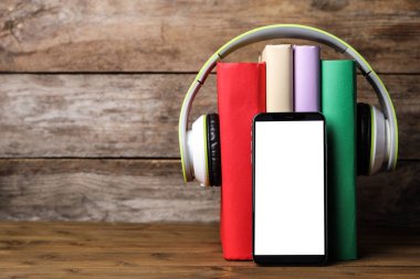 Modern kulaklıklı kitaplar ve ahşap masada akıllı telefon. Metin için boşluk