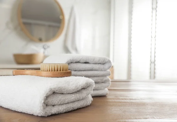 Hromada čistých ručníků a masážní kartáč na dřevěném stole v koupelně — Stock fotografie