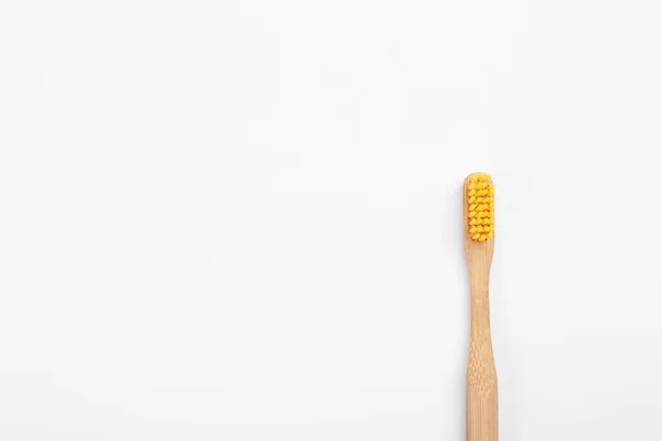 Бамбуковая зубная щетка с желтой щетиной, изолированная на белой, сверху — стоковое фото