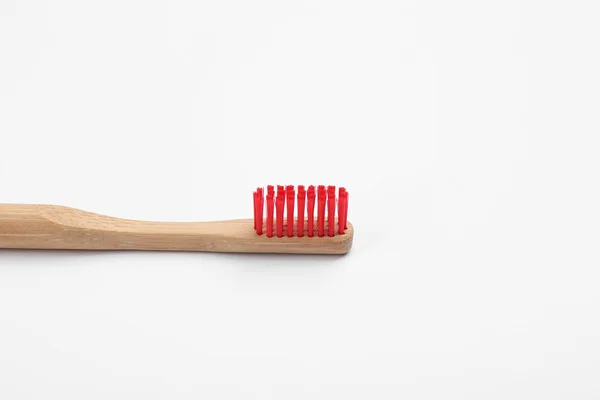 Бамбуковая зубная щетка с красной щетиной, изолированной на белом — стоковое фото