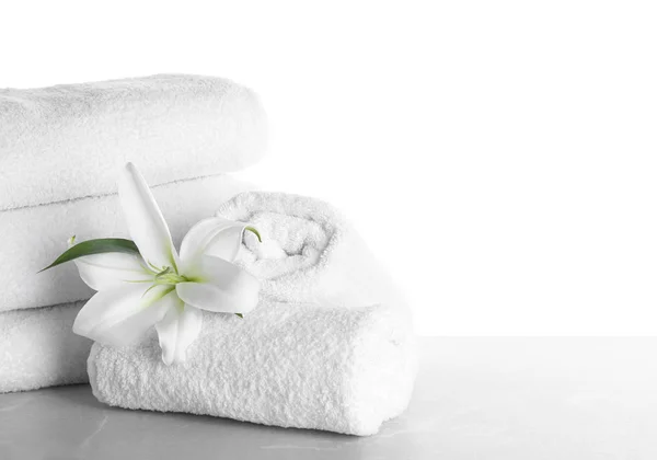 Fresh towels and lily flower on light grey marble table against — Stock Photo, Image