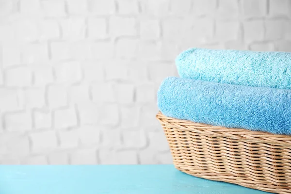 Плетений кошик з чистими м'якими рушниками для ванни на синьому дерев'яному столі . — стокове фото