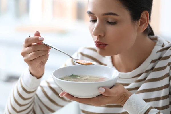 Young woman eating tasty vegetable soup indoors — Stock Photo, Image