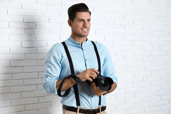 Fotógrafo profesional trabajando cerca de la pared de ladrillo blanco en studi —  Fotos de Stock