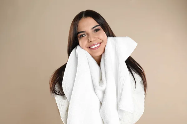 Jovem mulher esfregando o rosto com toalha no fundo bege — Fotografia de Stock