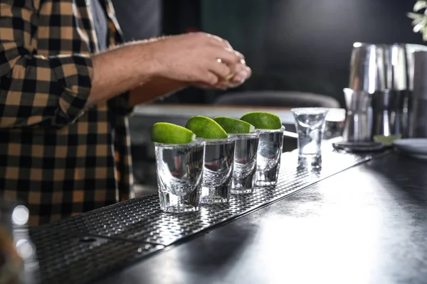 Mexican Tequila shots with lime slices on bar counter