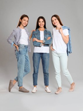 Gri arka planda şık kotlu bir grup genç kadın.