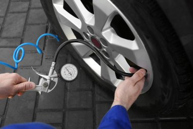 Tamirci araba servisinde lastik basıncını kontrol ediyor.