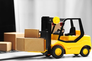 Oyuncak forklift ve dizüstü bilgisayarın yanındaki kutular. Lojistik ve toptan satış kavramı