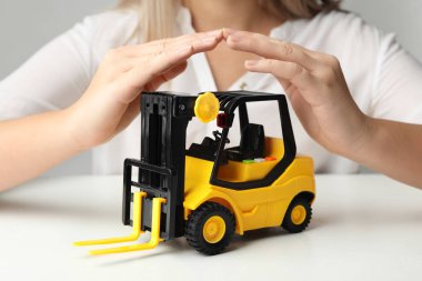 Beyaz masada oyuncak forklift kullanan kadın, yakın plan. Lojistik ve toptan satış kavramı