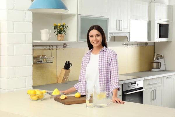 Piękna młoda kobieta przygotowuje cytrynową wodę w kuchni — Zdjęcie stockowe