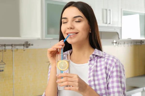 Wanita muda yang cantik minum air lemon di dapur — Stok Foto