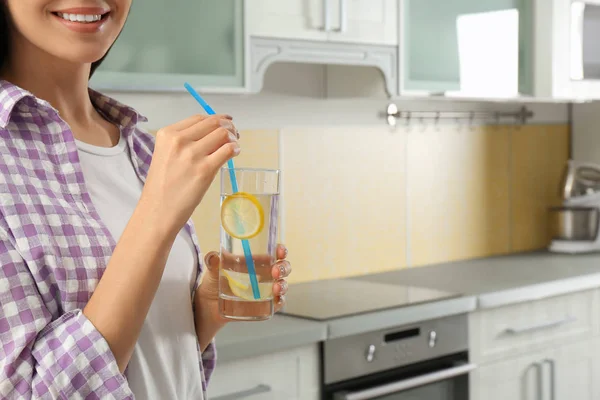 Giovane donna con acqua al limone in cucina, primo piano — Foto Stock