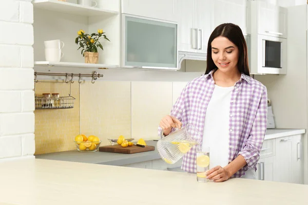 Bella donna versando acqua di limone nel bicchiere da brocca in kitch — Foto Stock