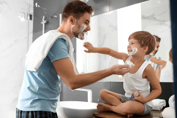 Pai e filho com espuma de barbear em seus rostos se divertindo no banho — Fotografia de Stock