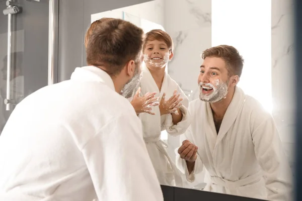 Papá e hijo con espuma de afeitar en las caras en el baño — Foto de Stock