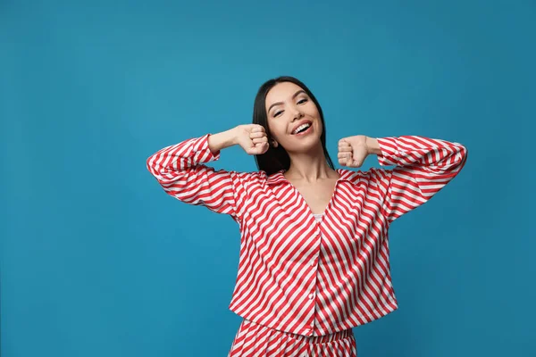 Mulher asiática bonita em pijama alongando-se no fundo azul . — Fotografia de Stock