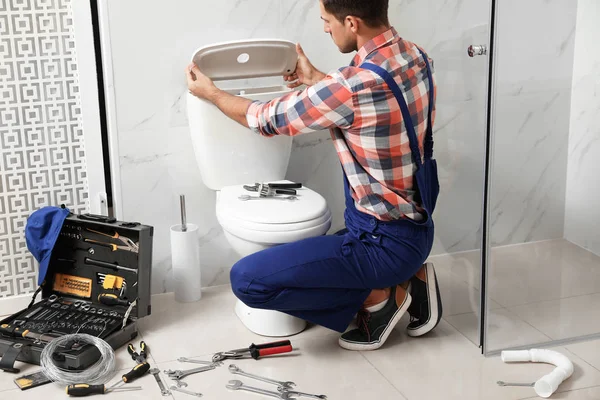 Professionele loodgieter werken met toilet kom in de badkamer — Stockfoto
