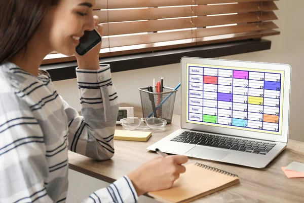 Jonge vrouw van plan haar schema met kalender app op laptop in — Stockfoto