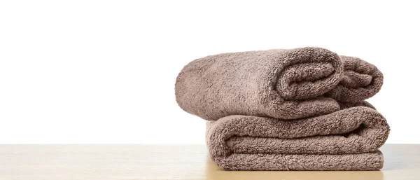 Складные чистые полотенца для ванной комнаты на столе против белого ba — стоковое фото