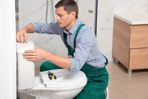 Fontanero profesional reparando inodoro en el baño — Foto de Stock