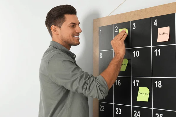 Snygg man sätta klibbig anteckning på ombord kalender — Stockfoto