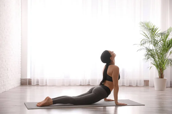 Mujer joven practicando cobra asana en estudio de yoga. Bhujangasana — Foto de Stock