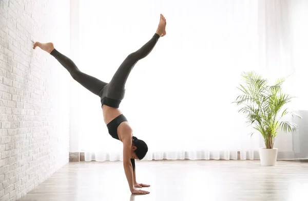 Mujer joven practicando asana de árbol orientado hacia abajo en estudio de yoga — Foto de Stock