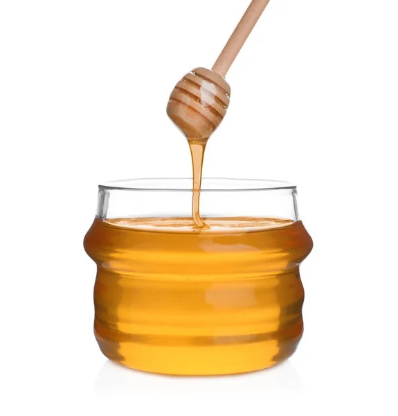 Honey dripping from wooden dipper into jar isolated on white — Stock Photo, Image