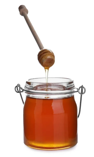 Honey dripping from wooden dipper into jar isolated on white — Stock Photo, Image