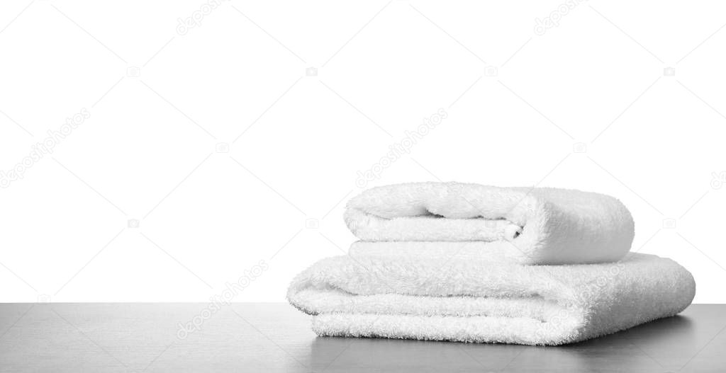 Folded fresh clean towels for bathroom on table against white ba