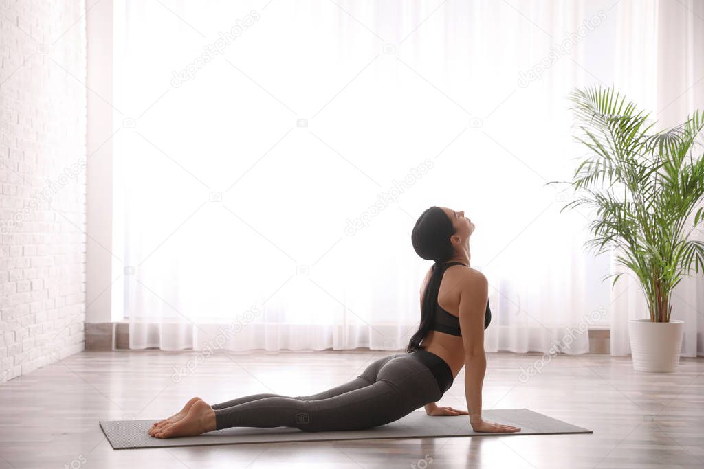 Young woman practicing cobra asana in yoga studio. Bhujangasana 