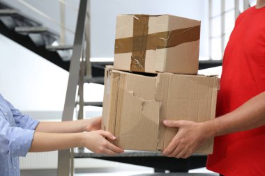 Kurye içerideki müşteriye hasarlı karton kutular veriyor, yakın plan. Kalitesiz dağıtım hizmeti