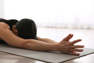 Yoga stüdyosunda uzun çocuk asanası pratiği yapan genç bir kadın.