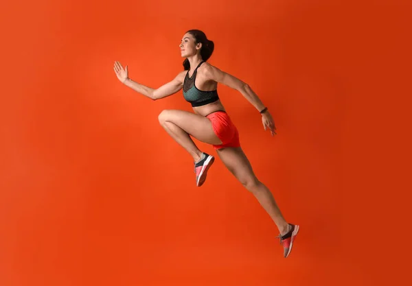 Mujer joven atlética corriendo sobre fondo rojo, vista lateral —  Fotos de Stock