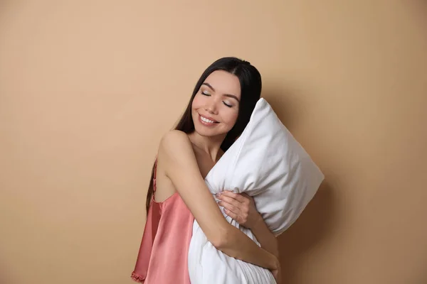 Vacker asiatisk kvinna med kudde på beige bakgrund. Sängdags — Stockfoto
