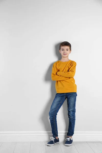 작고 귀여운 소년 이 가벼운 벽 가까이에 서 있는 모습 — 스톡 사진
