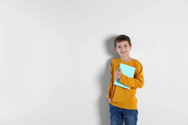 Cute little boy with book on light background, space for text — Stock Photo, Image