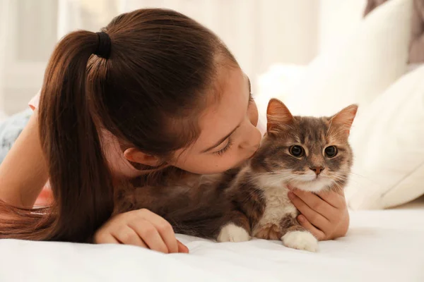 Nettes kleines Mädchen mit Katze, die zu Hause auf dem Bett liegt. erstes Haustier — Stockfoto