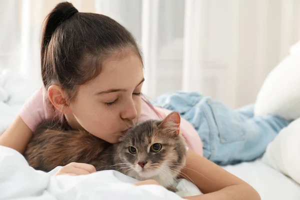 Nettes kleines Mädchen mit Katze, die zu Hause auf dem Bett liegt. erstes Haustier — Stockfoto