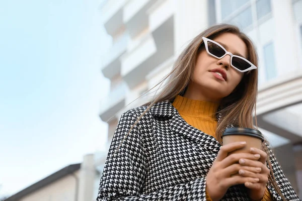 Mujer joven con taza de café en la calle de la ciudad por la mañana — Foto de Stock