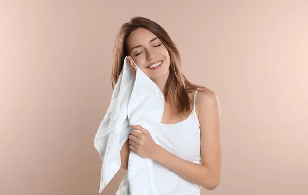 Młoda kobieta wycierająca twarz ręcznikiem na beżowym tle — Zdjęcie stockowe